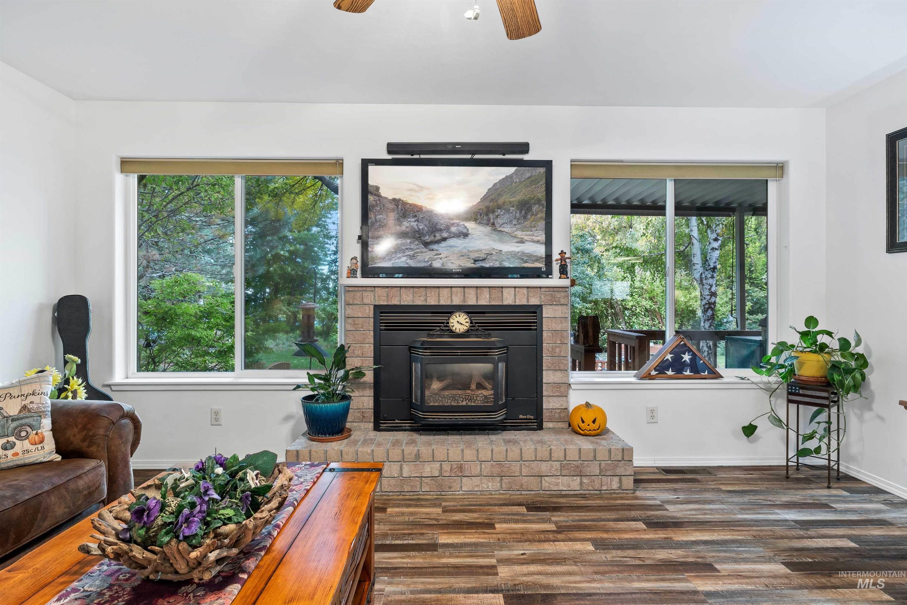 Living room with wood finished floors, a ceiling fan, and a fireplace