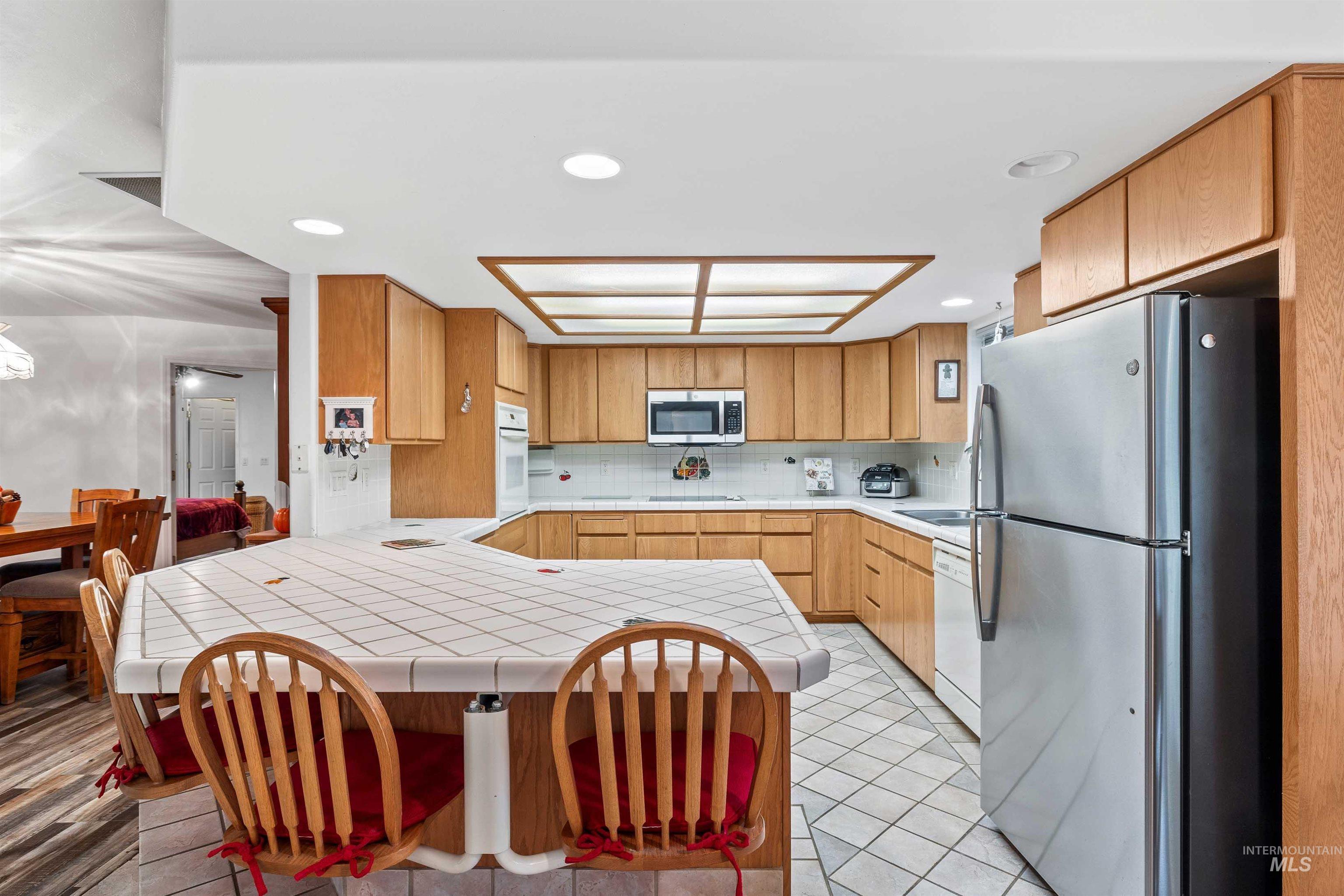 Kitchen featuring a peninsula, appliances with stainless steel finishes, backsplash, light tile patterned floors, and recessed lighting