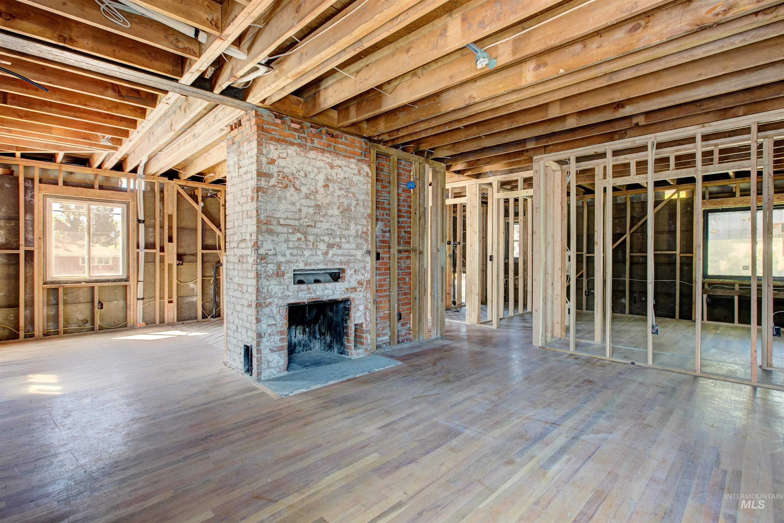 Unfurnished living room featuring a brick fireplace and wood finished floors