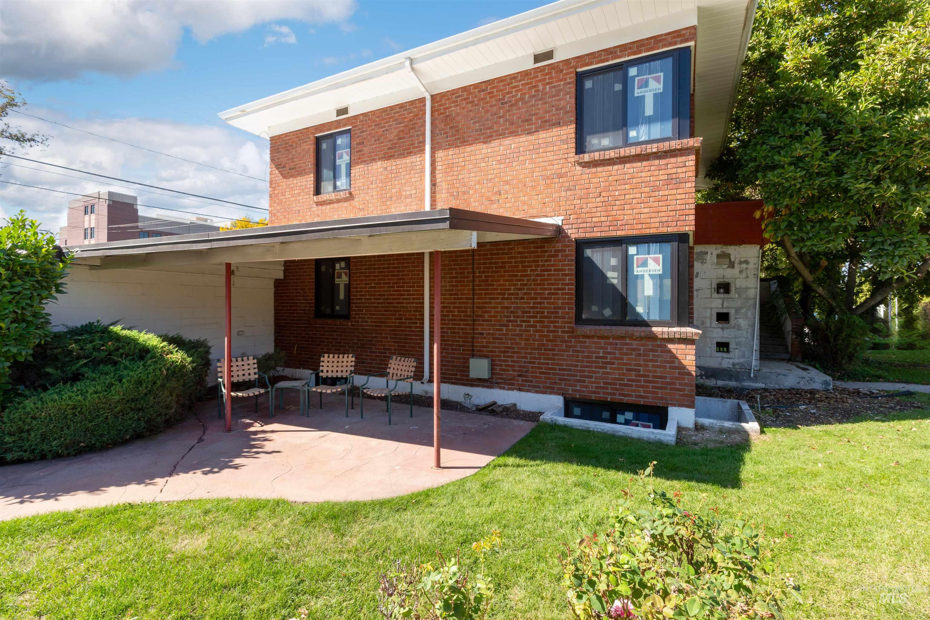 Rear view of house with a lawn, brick siding, and a patio