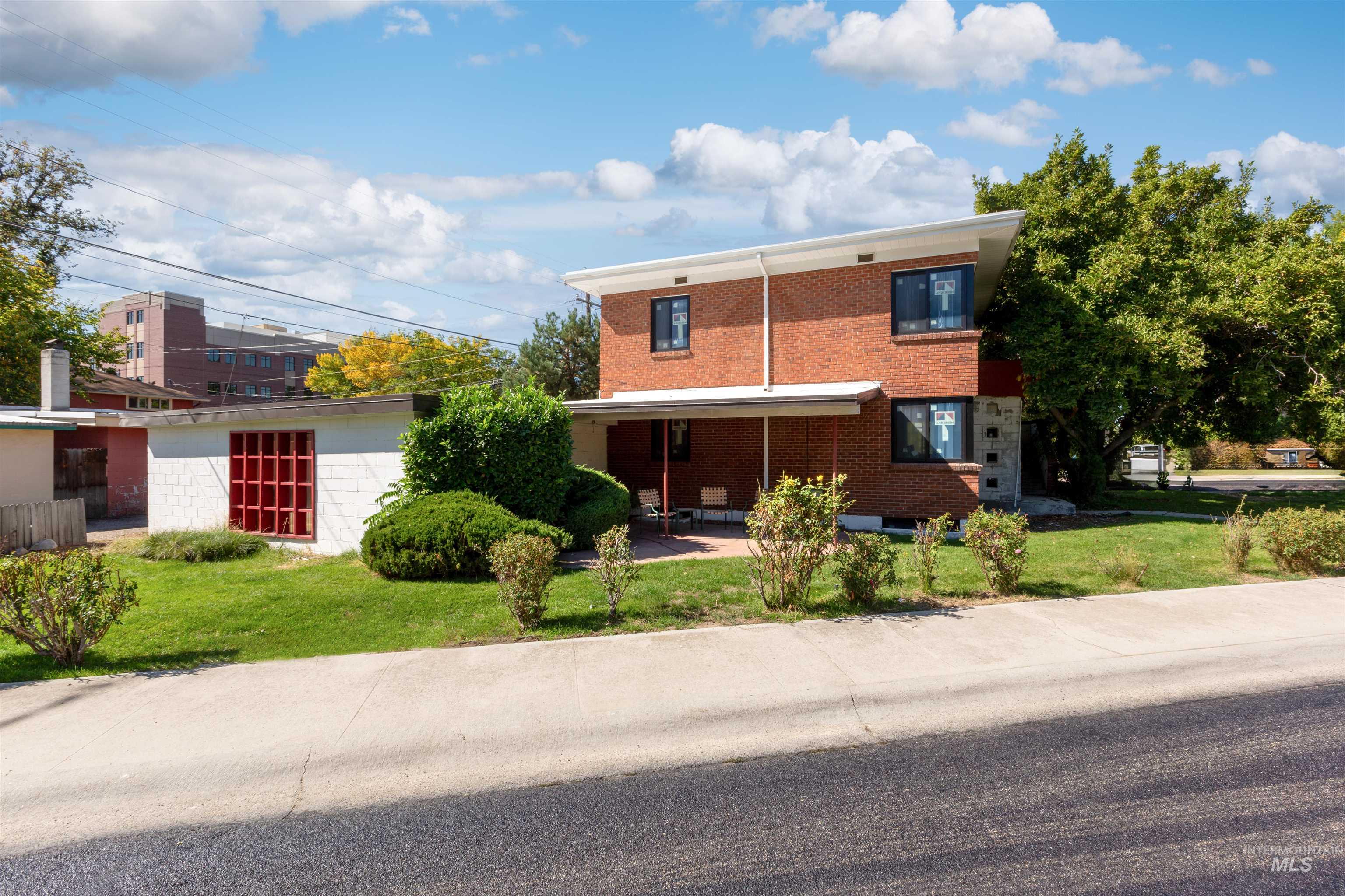 View of front of property featuring a front yard, brick siding, and a patio