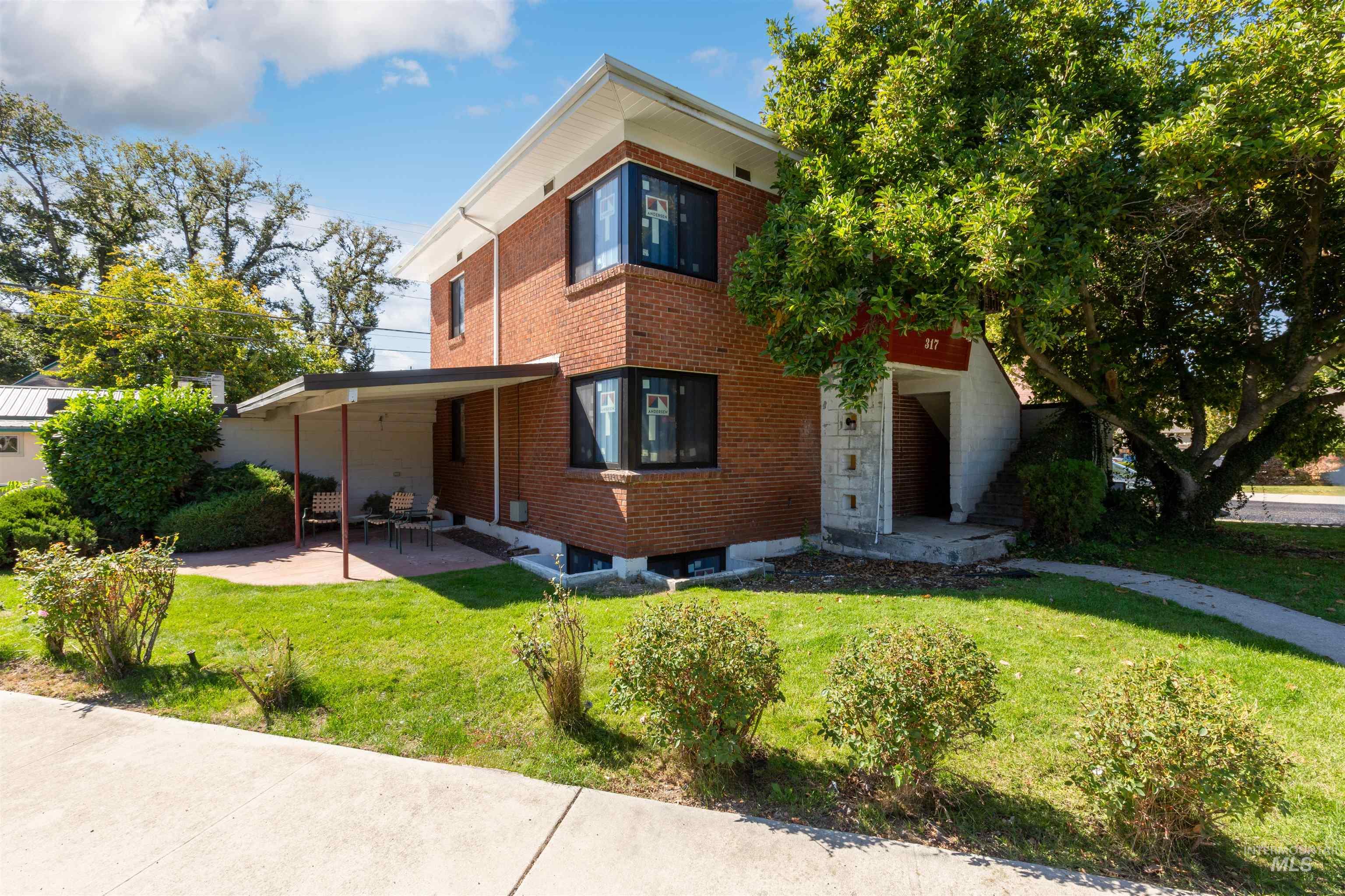 Rear view of property featuring a lawn and brick siding