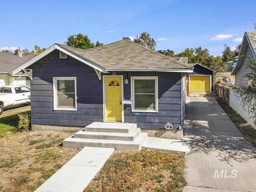 Bungalow with an outbuilding, a shingled roof, and concrete driveway