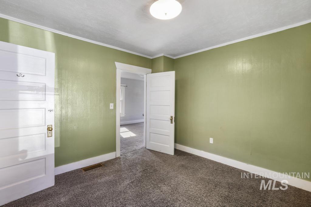 Unfurnished bedroom featuring dark carpet and crown molding