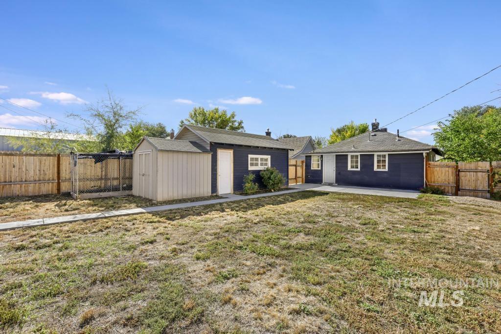 Back of property with a fenced backyard, a storage unit, and a patio