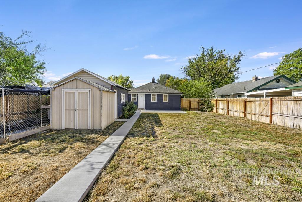 Rear view of property with a fenced backyard and a storage shed