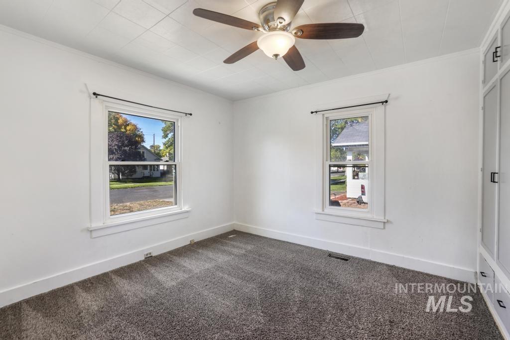 Empty room featuring dark colored carpet and a ceiling fan
