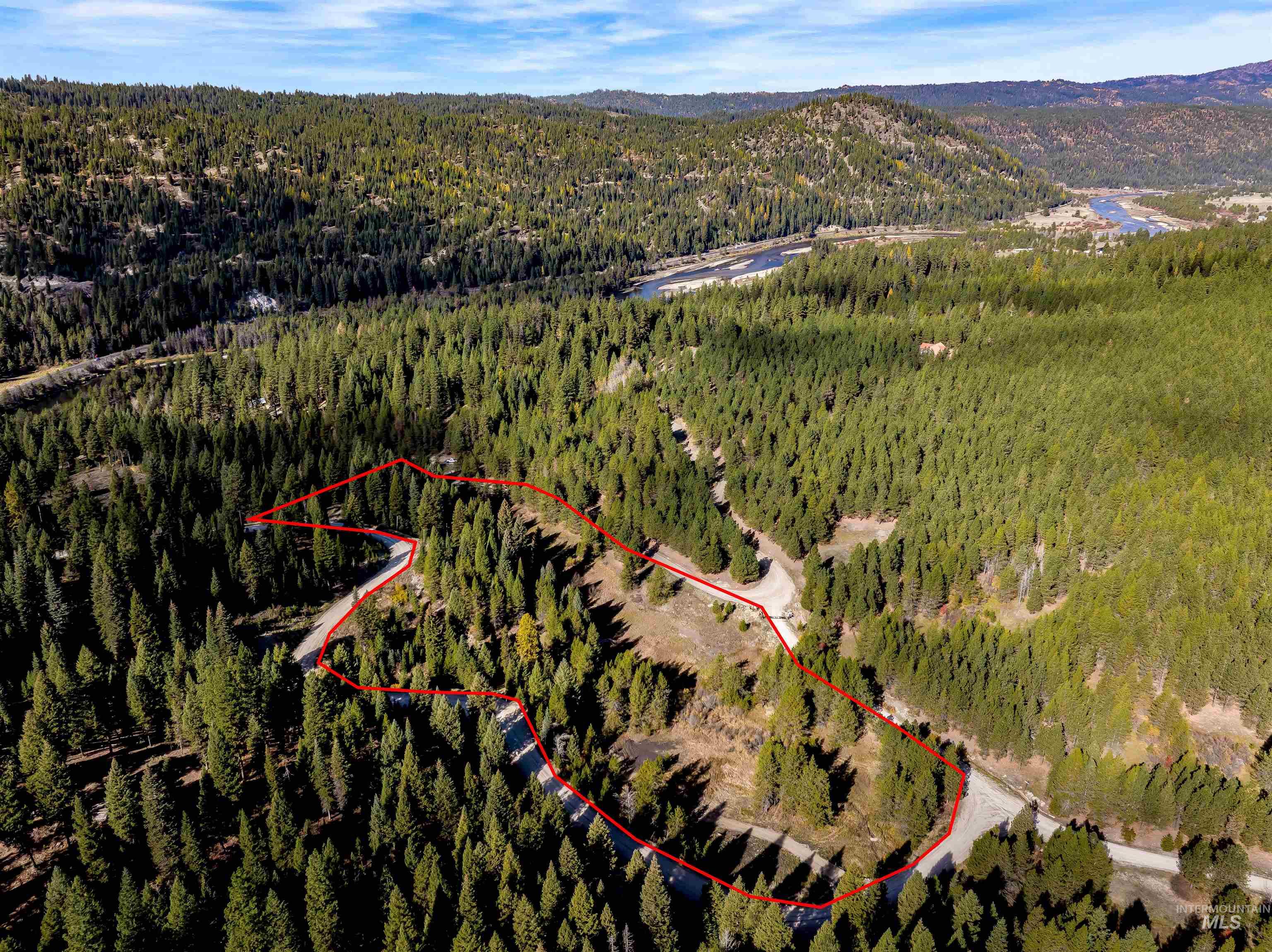 Aerial view of property and surrounding area with property parcel outlined and a mountainous background