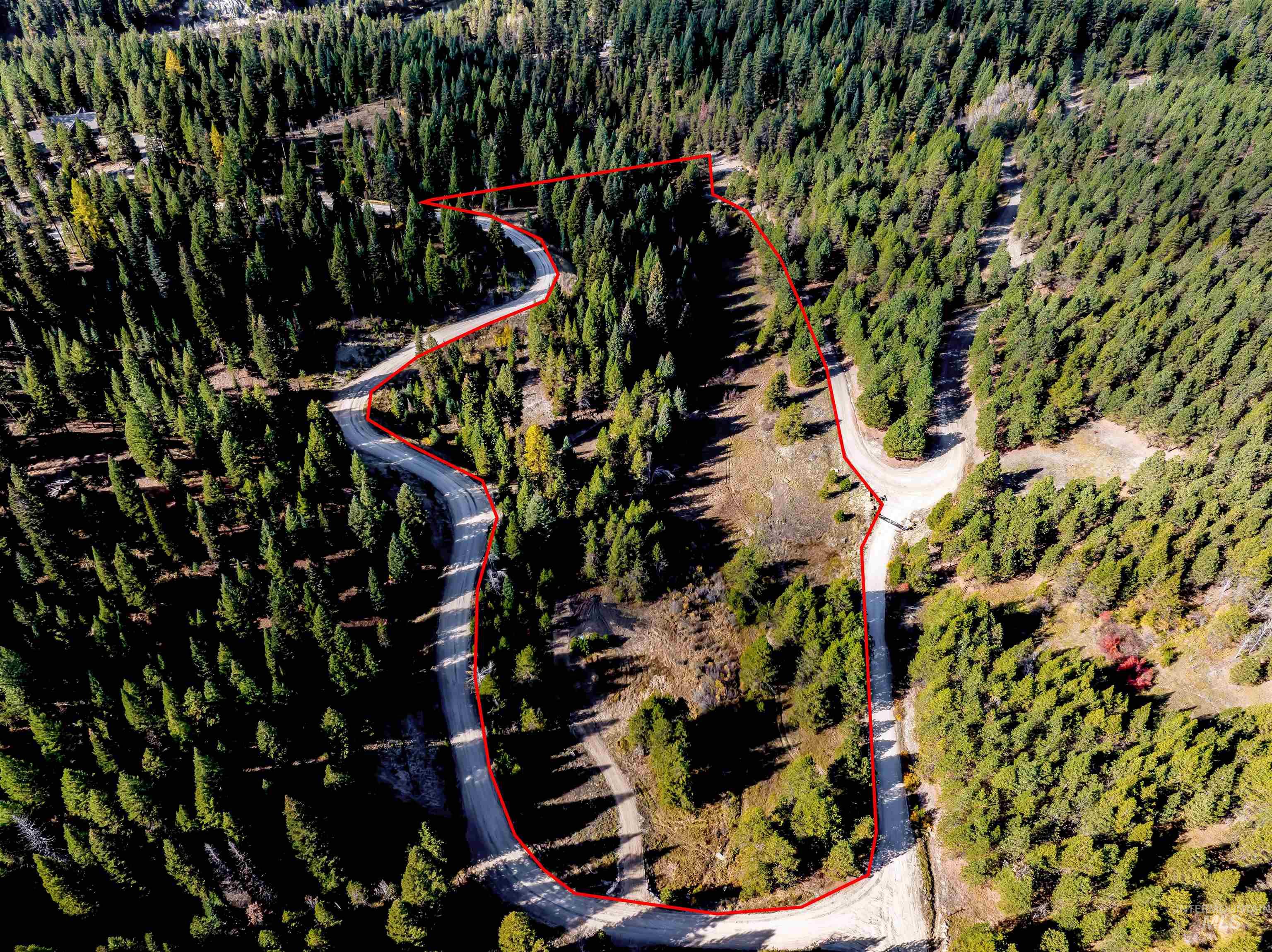 Aerial view of property and surrounding area featuring property parcel outlined and a heavily wooded area
