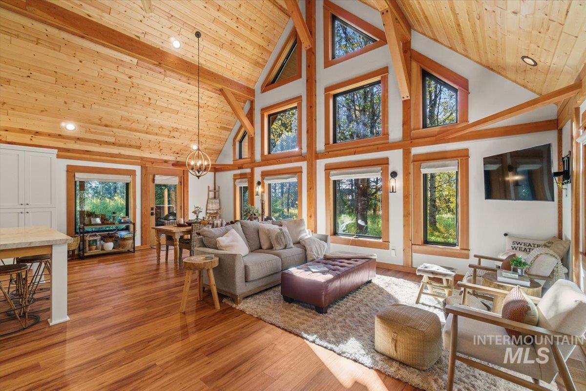 Living room with high vaulted ceiling, light wood finished floors, wood ceiling, a chandelier, and recessed lighting