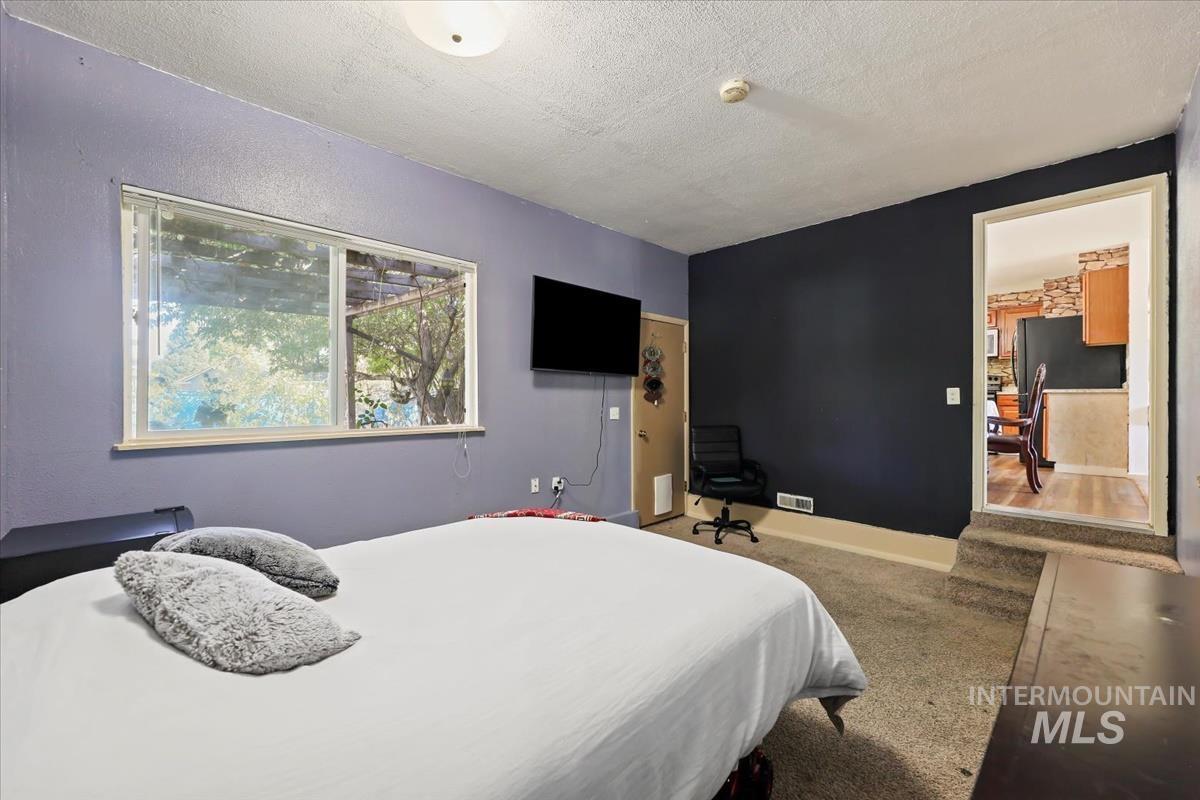Carpeted bedroom featuring a textured ceiling and freestanding refrigerator