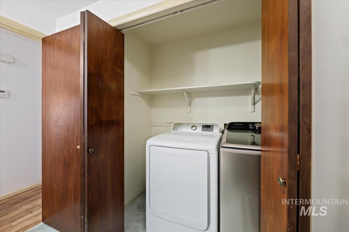Washroom with washer and dryer and light wood finished floors