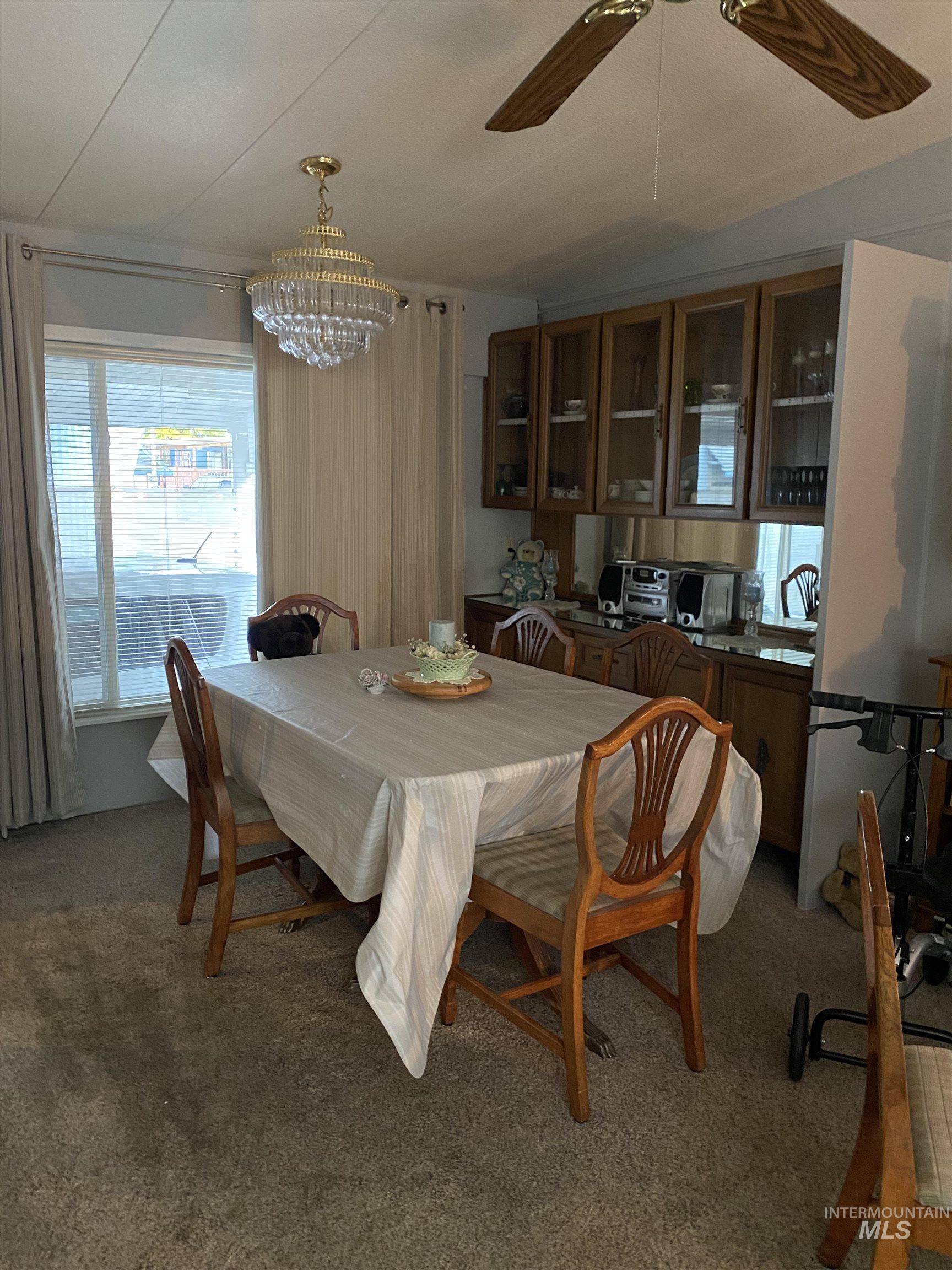 Dining area featuring carpet, a chandelier, and a ceiling fan