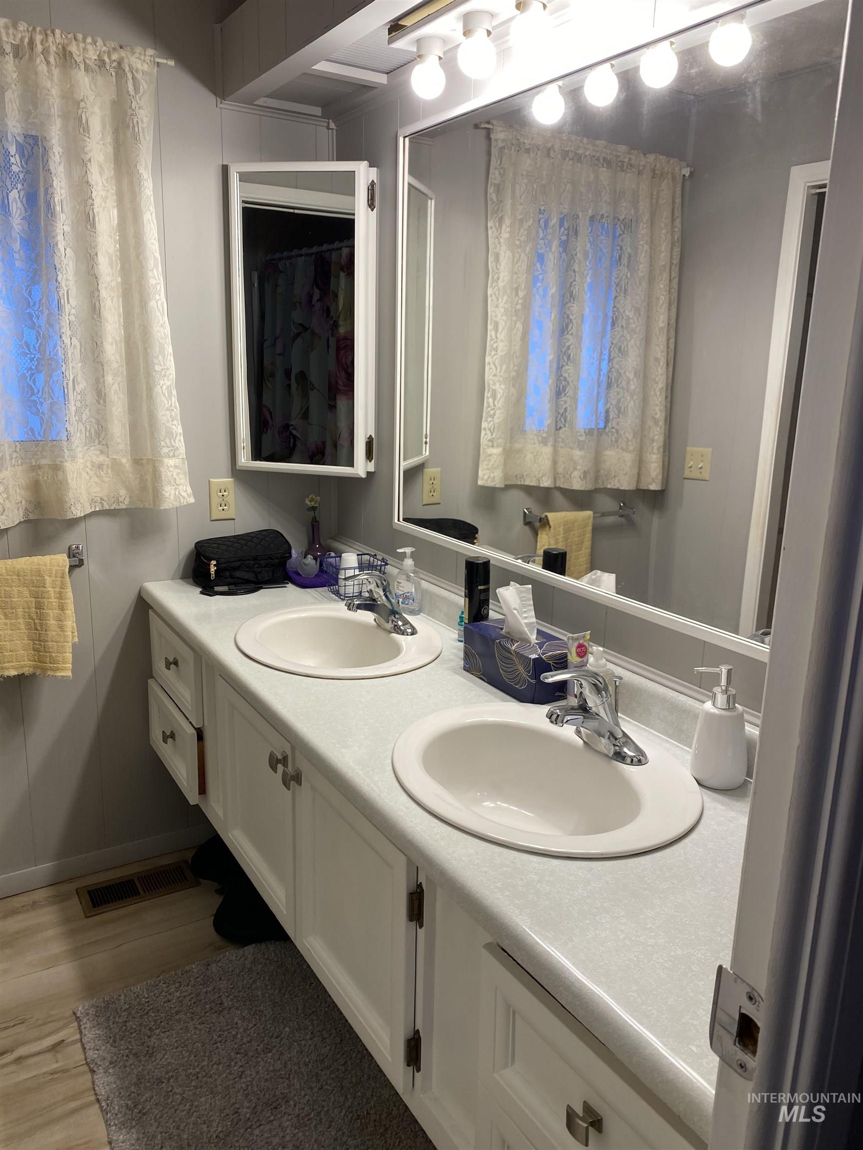 Bathroom with double vanity and light wood finished floors