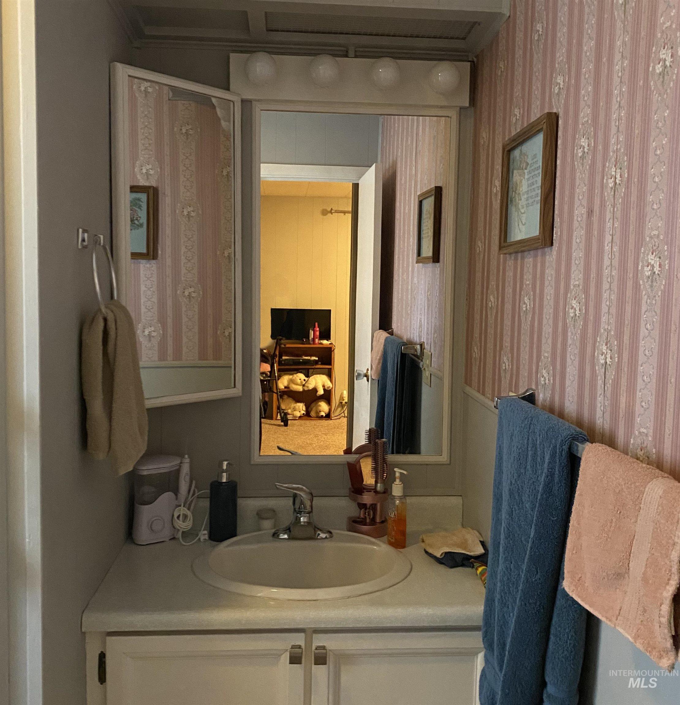 Bathroom with vanity and wallpapered walls