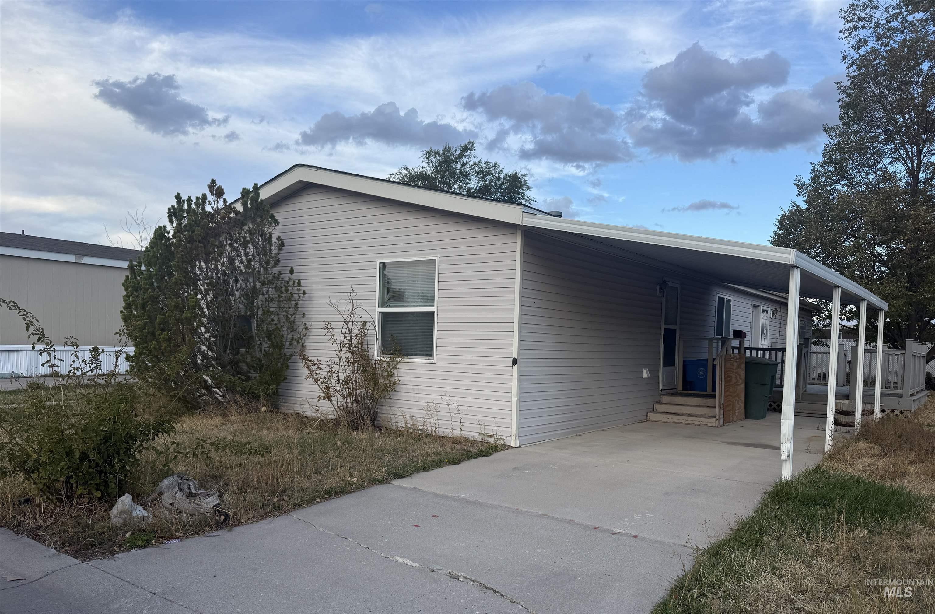 View of front facade with concrete driveway and an attached carport