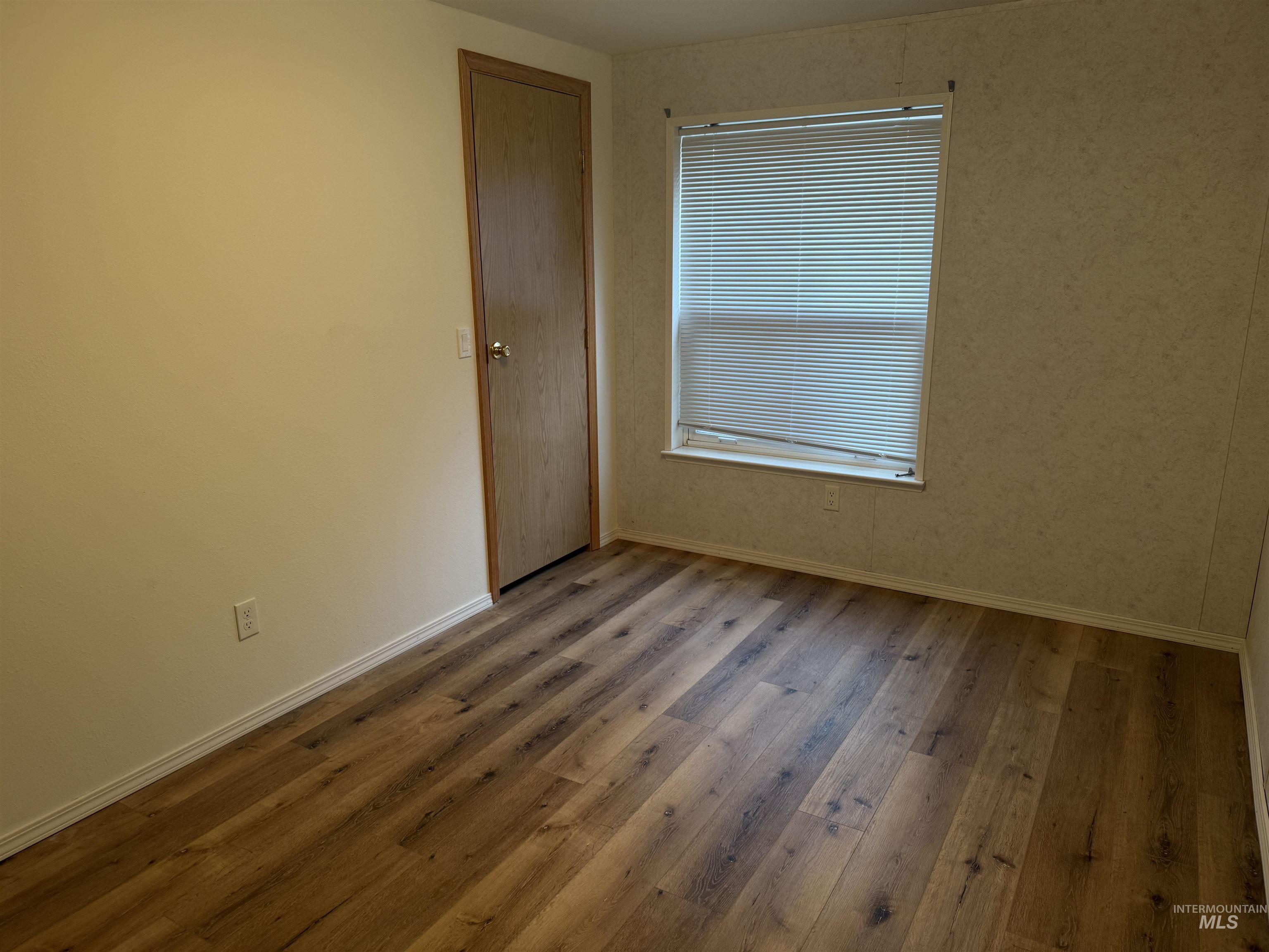 Empty room with light wood-type flooring and baseboards