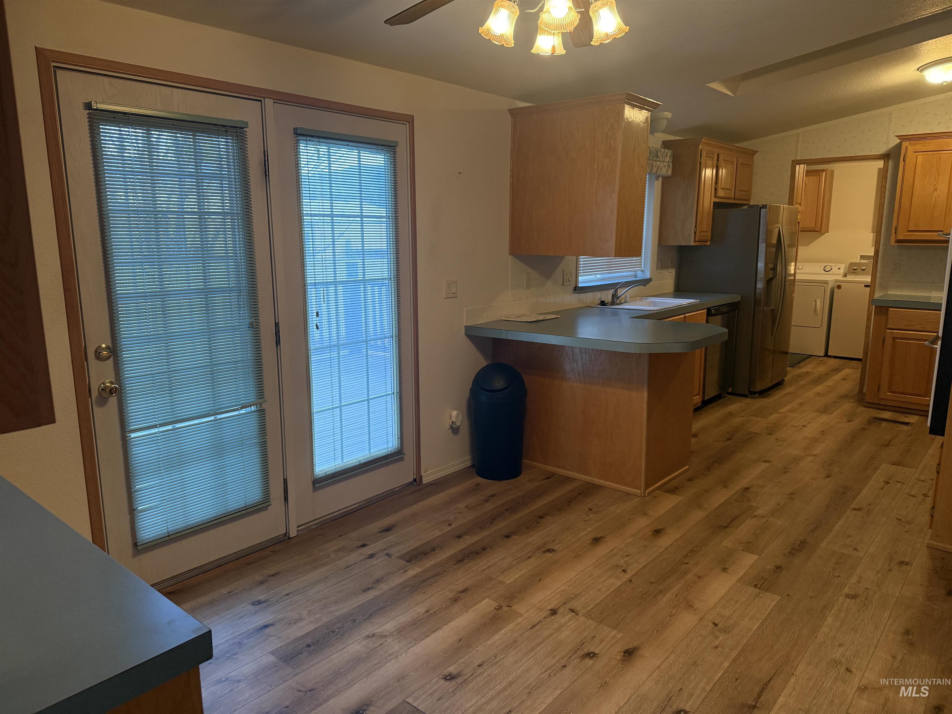 Kitchen with separate washer and dryer, plenty of natural light, light wood-style flooring, a peninsula, and vaulted ceiling