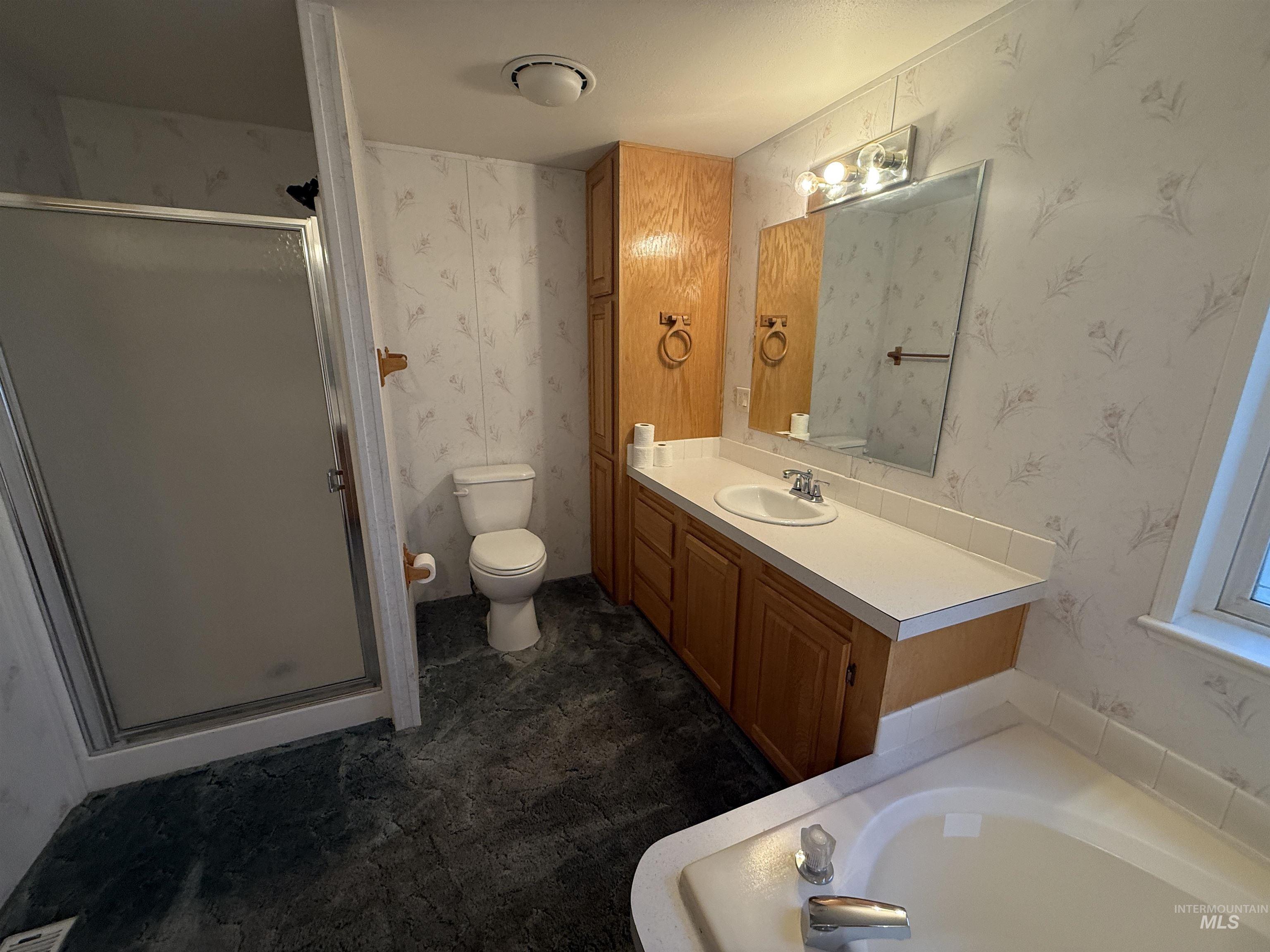Full bath featuring wallpapered walls, a bath, a stall shower, and vanity
