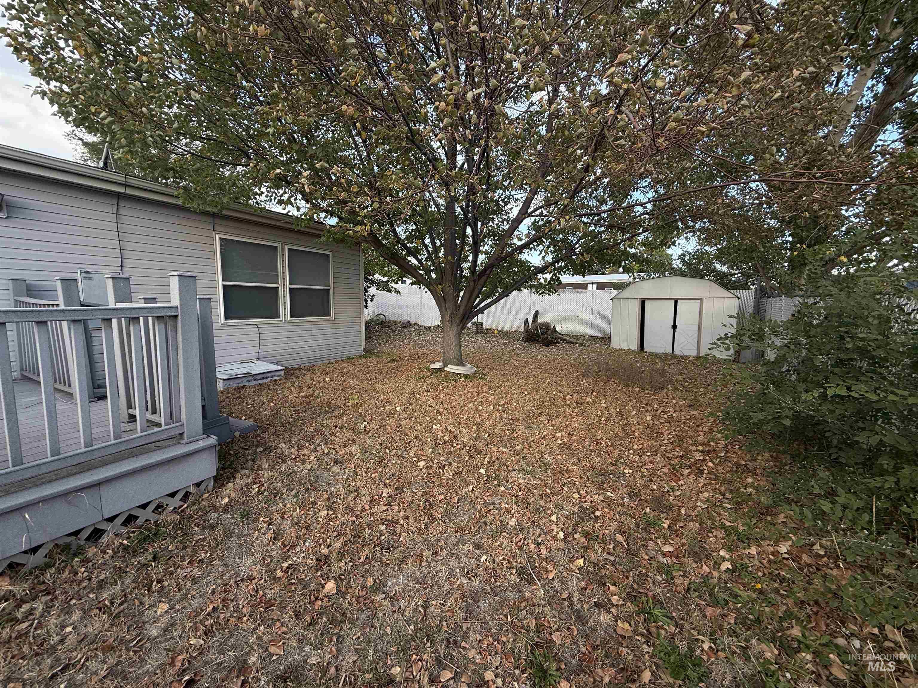 Fenced backyard with a deck and a storage unit