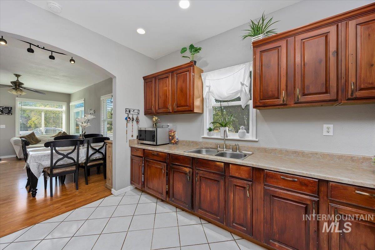 Kitchen with open floor plan, light tile patterned floors, light countertops, stainless steel microwave, and recessed lighting