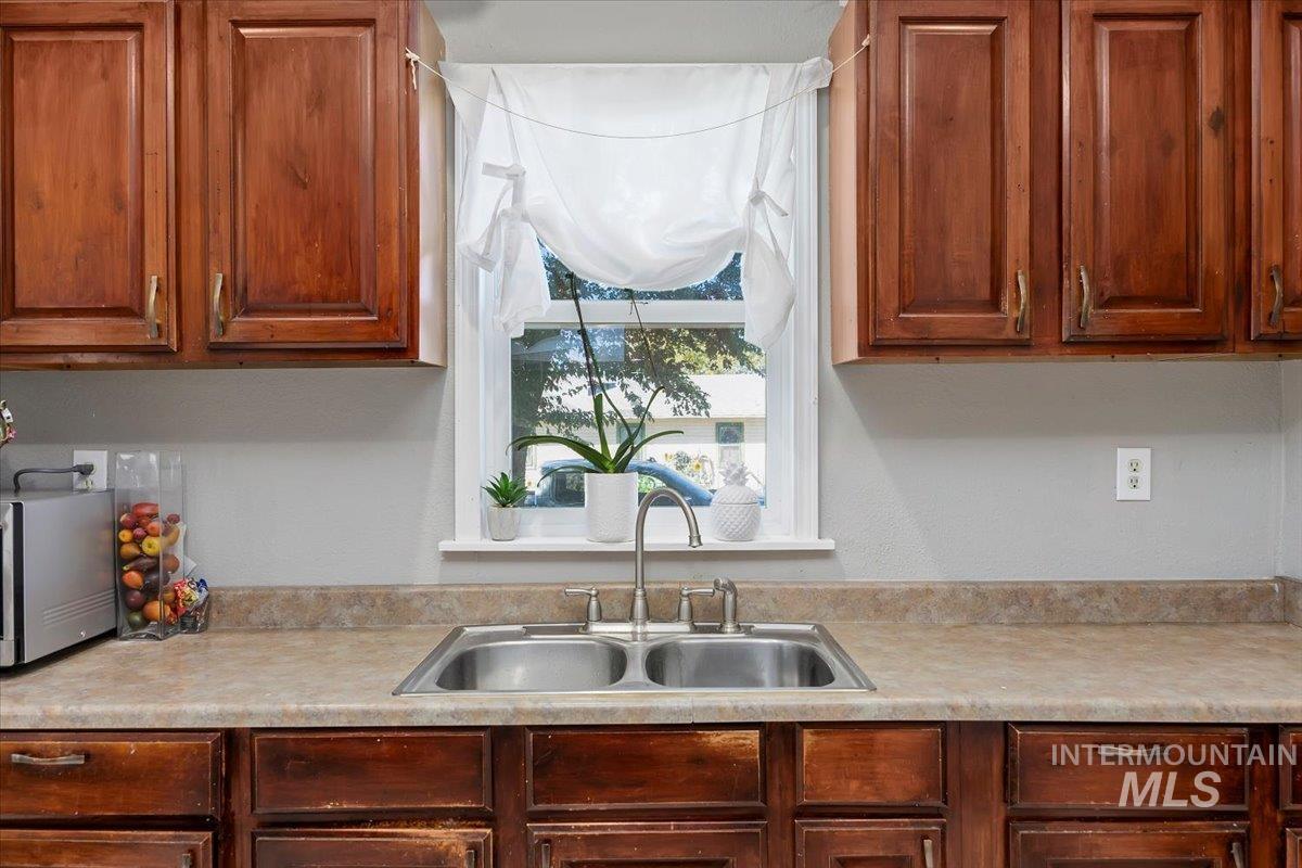 Kitchen with light countertops, brown cabinetry, and stainless steel microwave