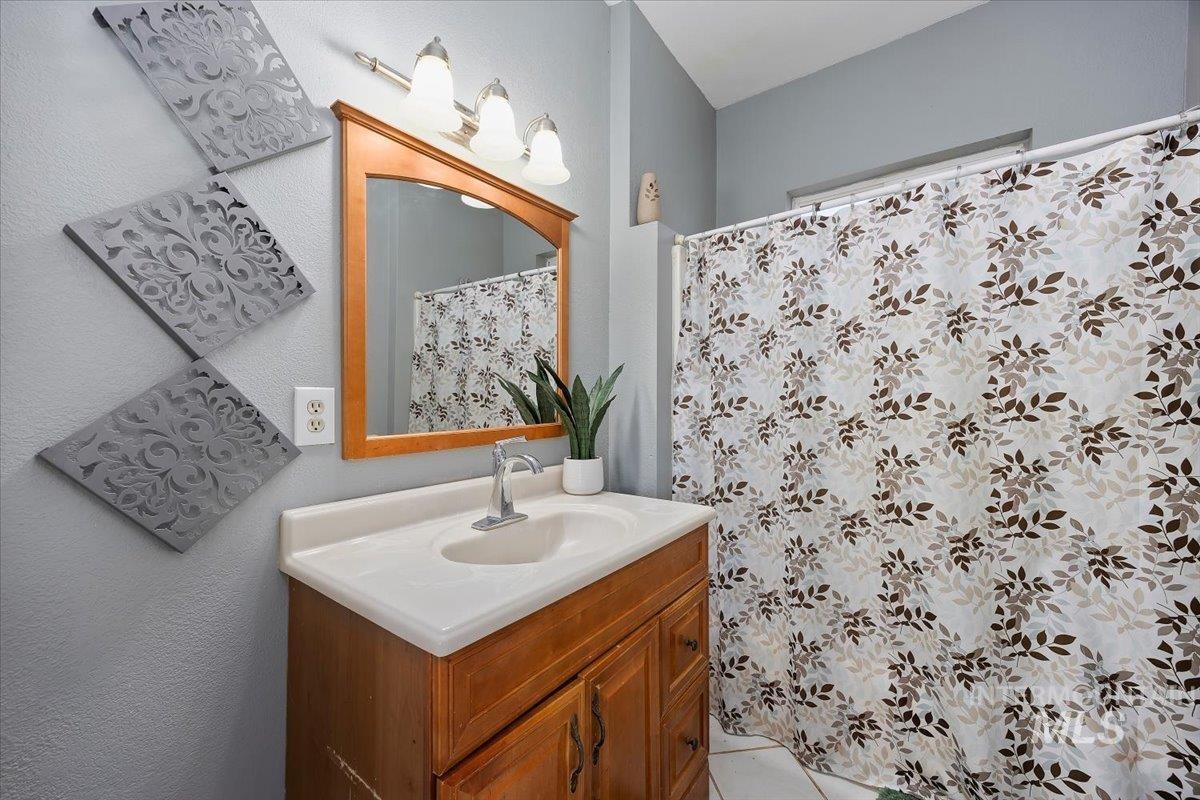 Bathroom with vanity, a textured wall, and a shower with shower curtain