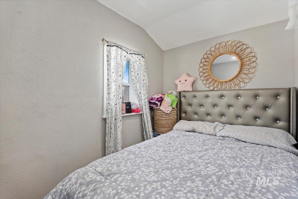 Bedroom with a textured wall and vaulted ceiling