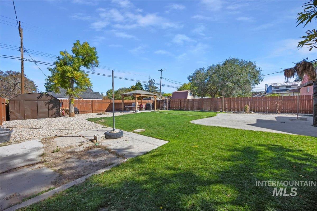 Fenced backyard featuring a gazebo, a patio area, and a storage unit