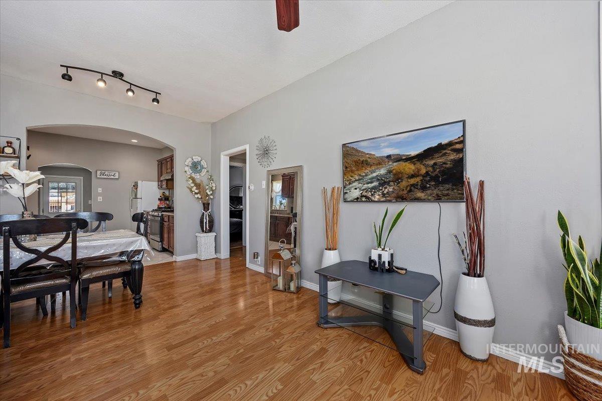 Dining room with light wood-style flooring, a ceiling fan, and arched walkways