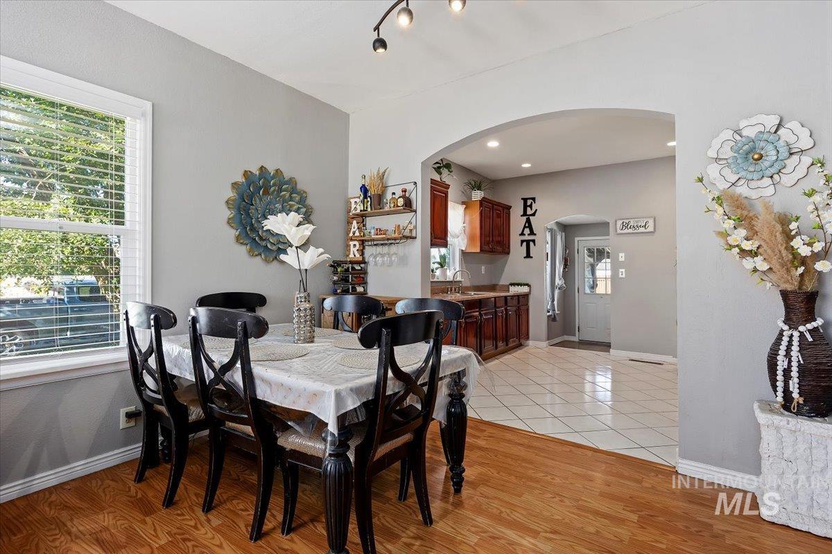 Dining space featuring light wood finished floors, arched walkways, and recessed lighting