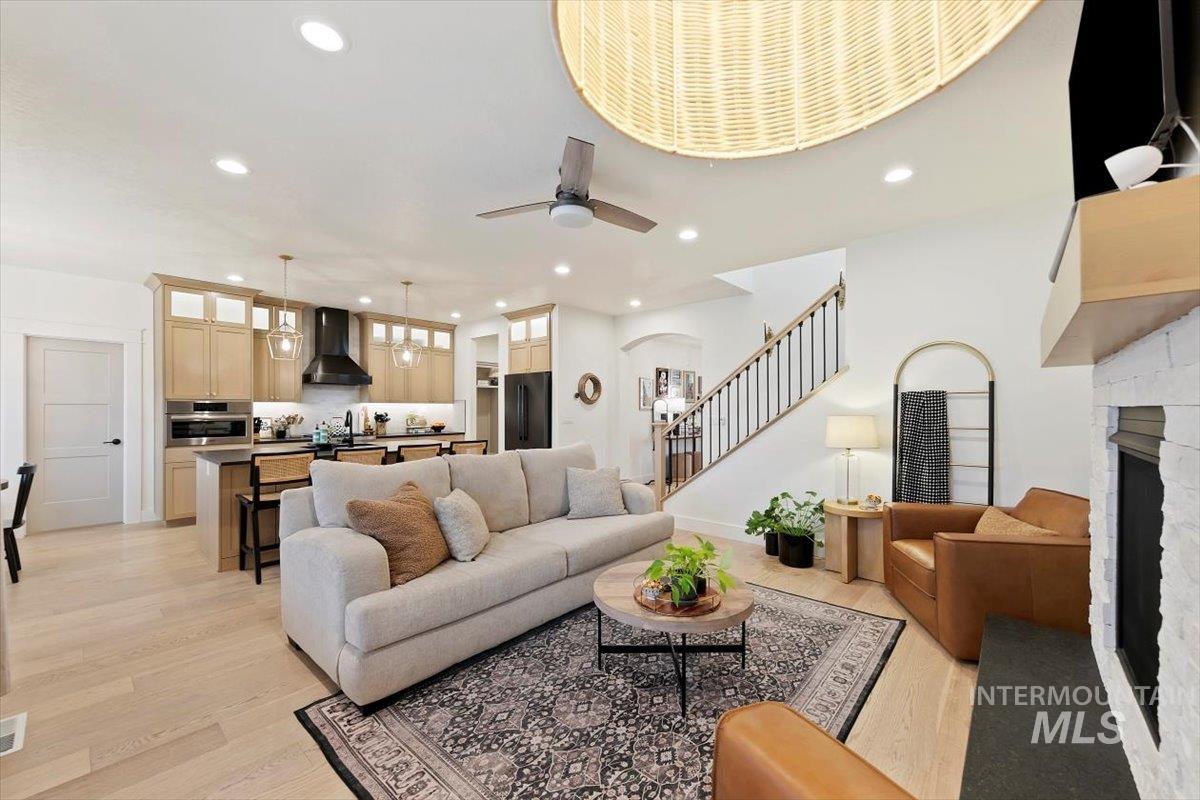 Living area featuring light wood-style floors, recessed lighting, stairs, arched walkways, and a fireplace