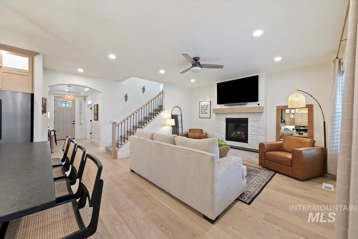 Living area with arched walkways, stairs, light wood-type flooring, recessed lighting, and a ceiling fan
