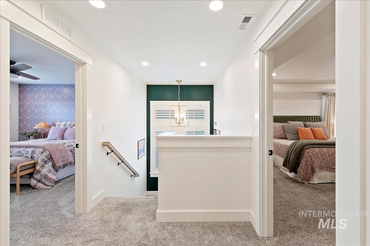 Hallway featuring carpet floors, an upstairs landing, recessed lighting, and a chandelier