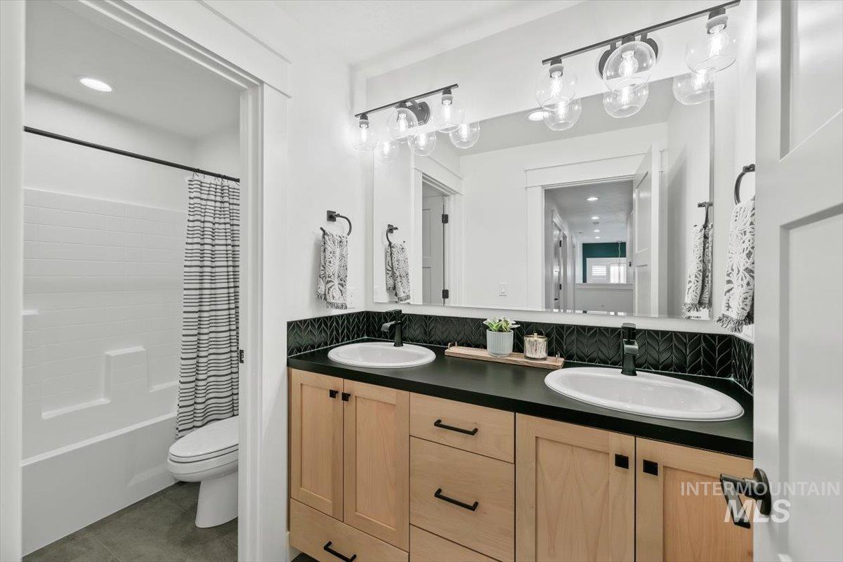 Bathroom featuring shower / bath combo with shower curtain, double vanity, decorative backsplash, tile patterned flooring, and recessed lighting