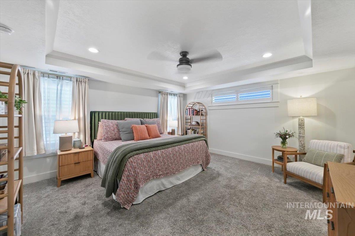Bedroom with carpet flooring, a raised ceiling, a ceiling fan, and recessed lighting