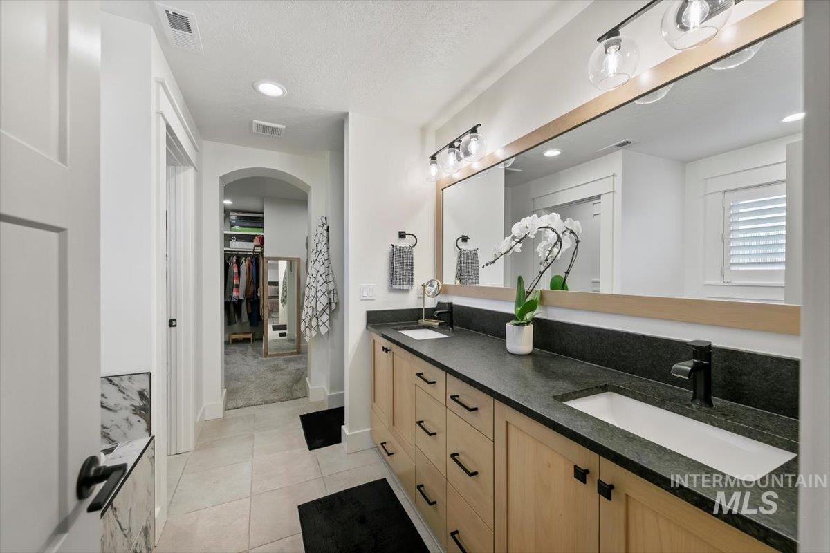 Full bathroom with double vanity, light tile patterned flooring, a walk in closet, recessed lighting, and a textured ceiling