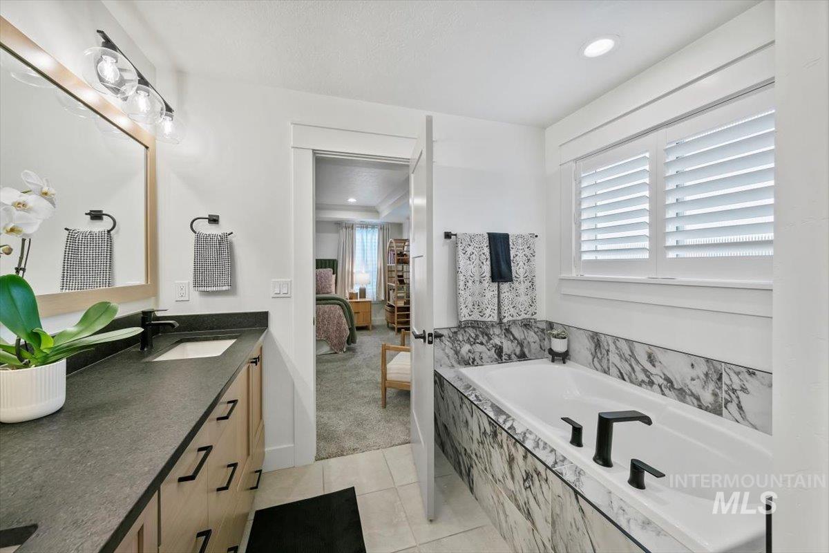 Full bathroom featuring plenty of natural light, vanity, a bath, light tile patterned flooring, and recessed lighting