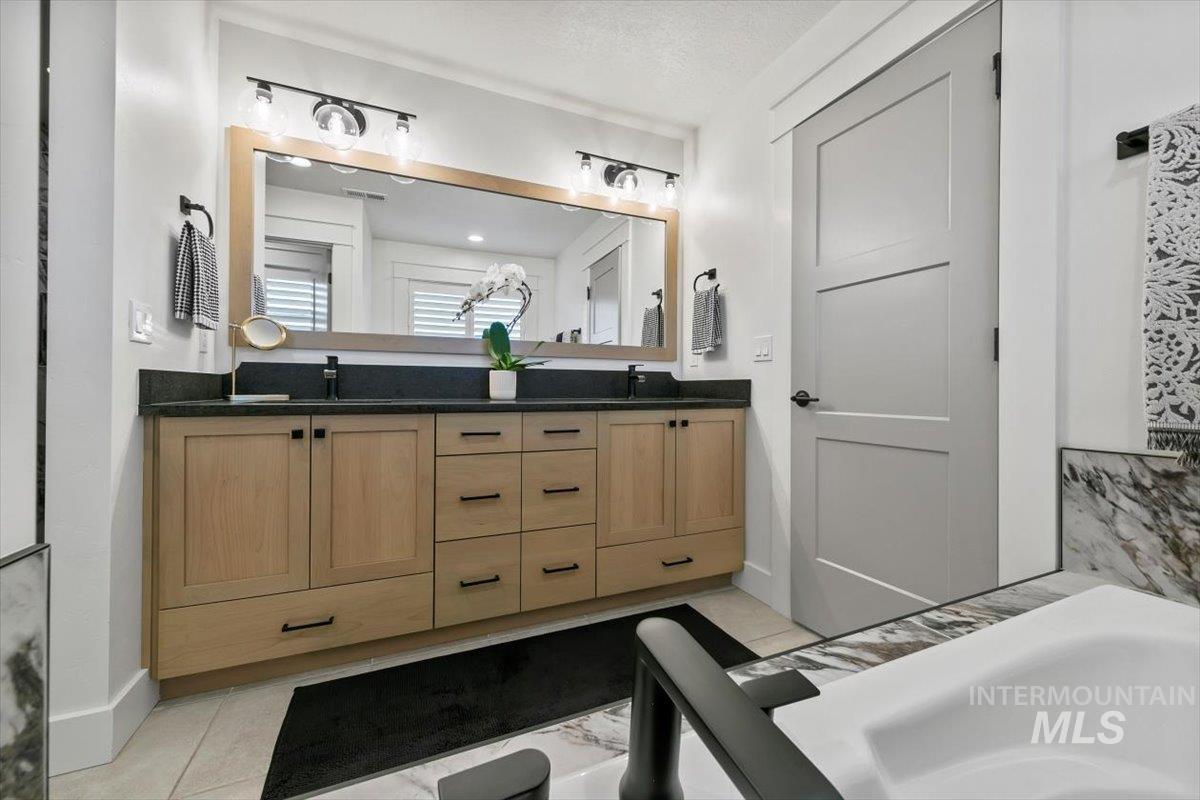 Bathroom with double vanity, a bath, and light tile patterned flooring