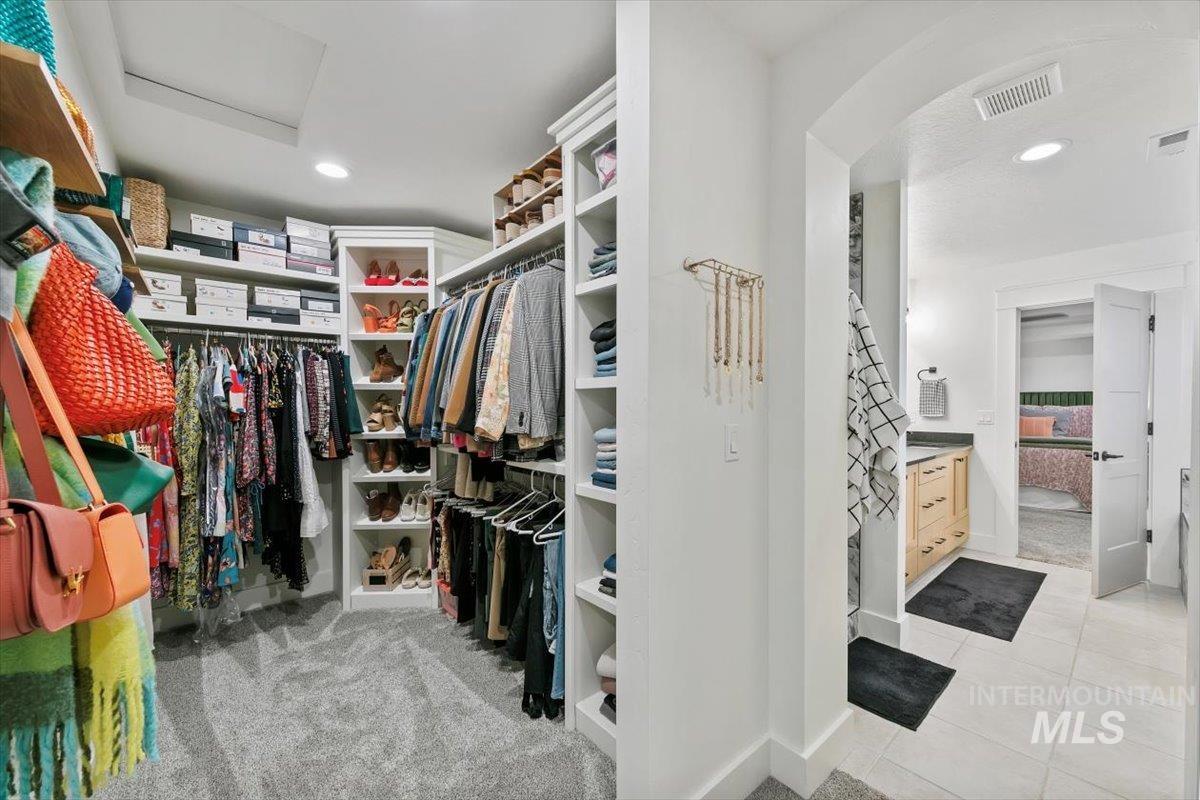 Spacious closet featuring light carpet, light tile patterned flooring, and attic access