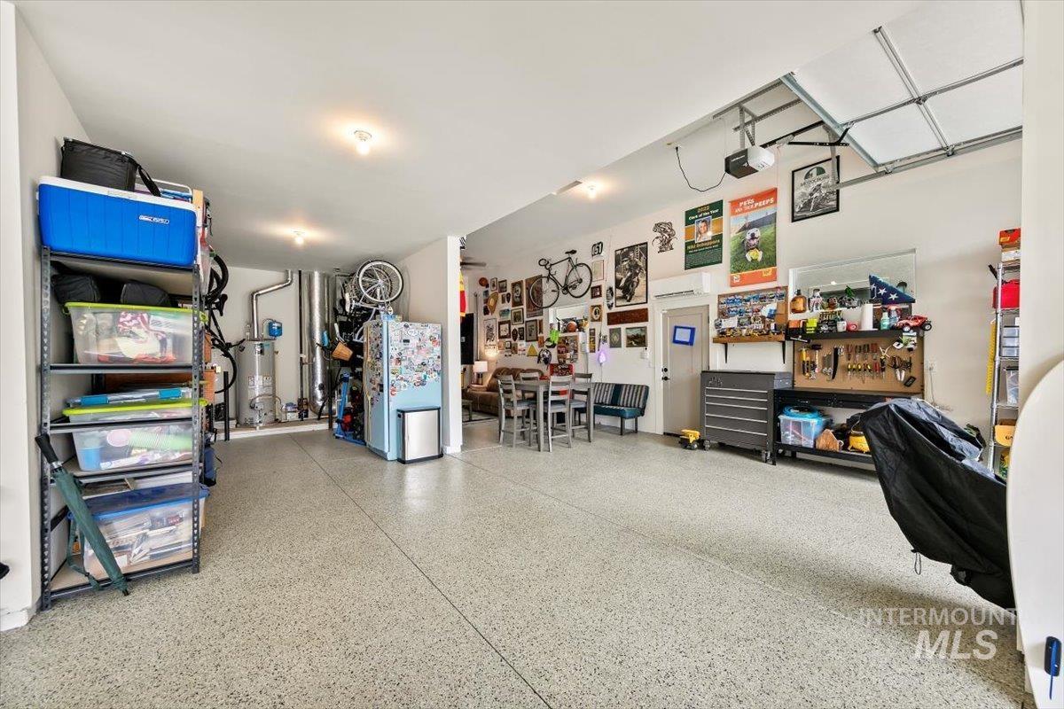 Garage featuring freestanding refrigerator, gas water heater, and a garage door opener