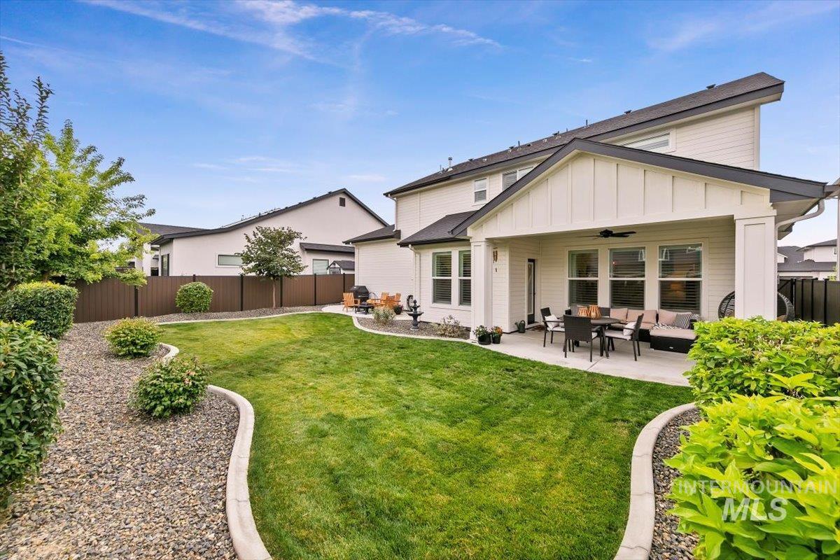 Back of property with outdoor lounge area, a fenced backyard, a ceiling fan, a patio, and board and batten siding
