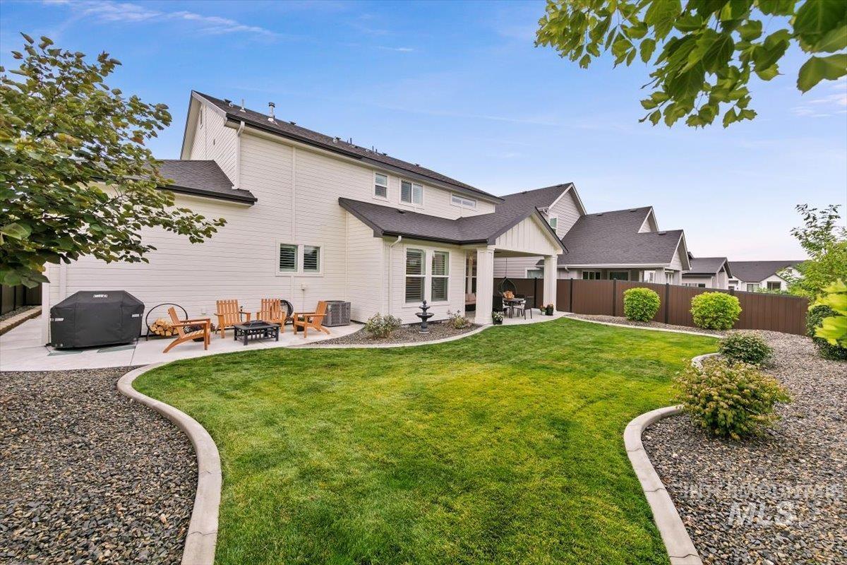 Back of property with a patio area, roof with shingles, board and batten siding, and an outdoor fire pit