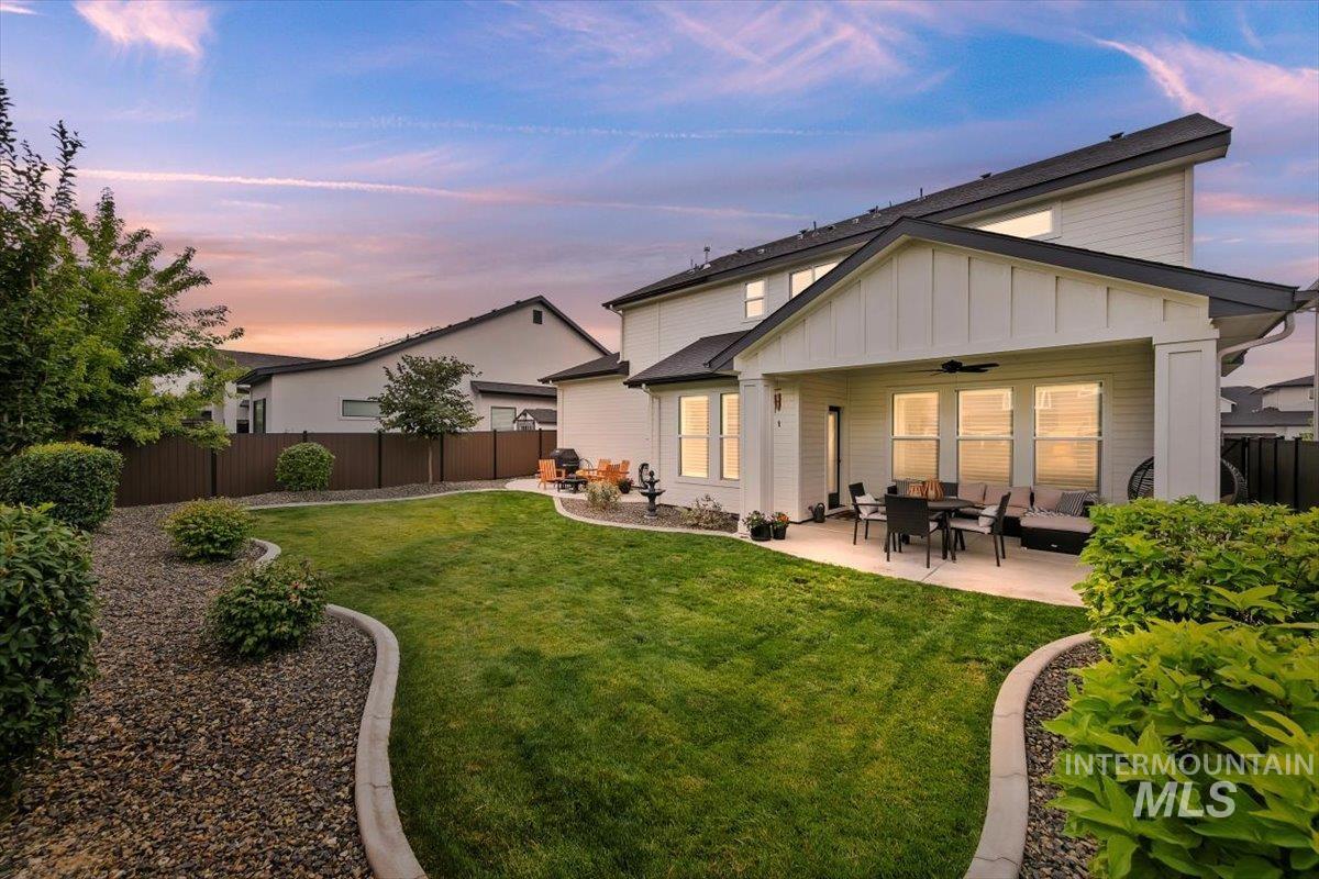 Back of house featuring ceiling fan, board and batten siding, a fenced backyard, a patio, and outdoor lounge area