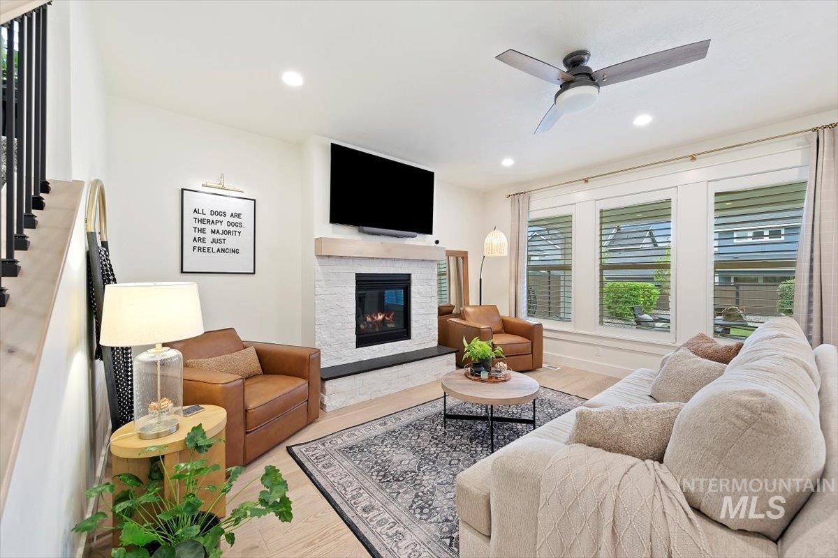 Living area featuring recessed lighting, wood finished floors, a stone fireplace, and a ceiling fan