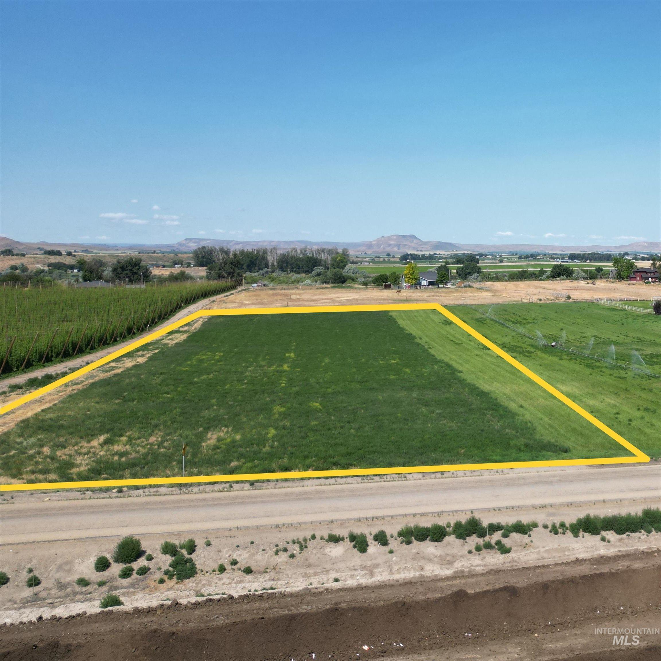 Aerial view of sparsely populated area with a mountainous background, property boundaries highlighted, and extensive farmland