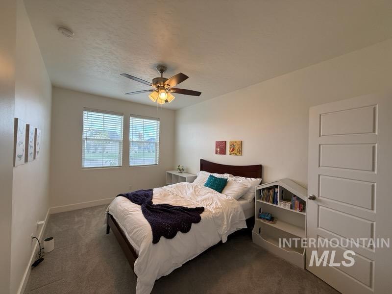 Carpeted bedroom featuring baseboards and ceiling fan