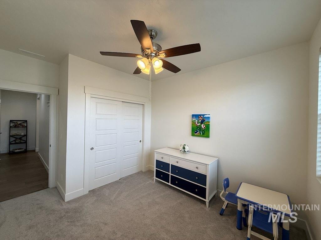 Carpeted bedroom with a closet and a ceiling fan