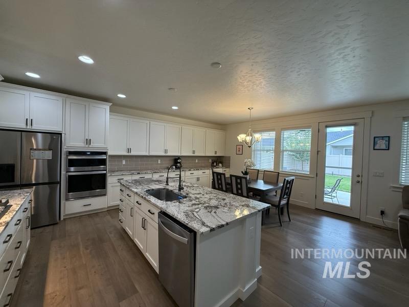 Kitchen featuring appliances with stainless steel finishes, white cabinets, pendant lighting, dark wood finished floors, and recessed lighting