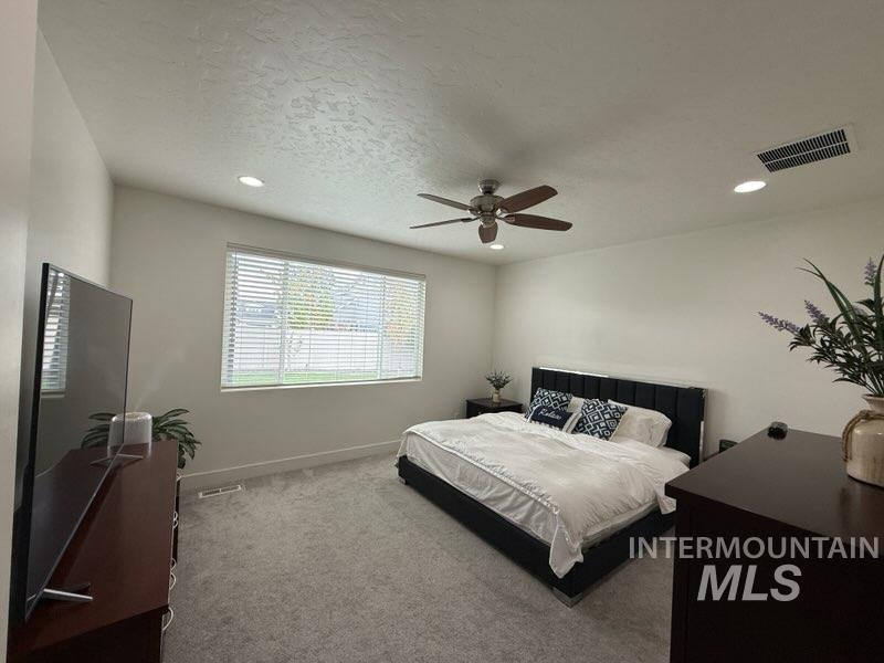Bedroom with carpet flooring, ceiling fan, recessed lighting, and a textured ceiling